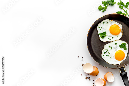 Photos Fried eggs on frying pan - breakfast - on white table from above space for text