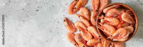 Prawns in a wooden bowl on a light gray table. Lots of shrimp in a bowl. Shrimp close-up. Top view with space for text. Banner