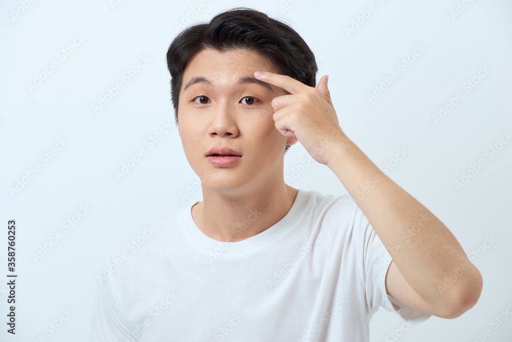 Young man squeezing a pimple, men's skincare concept Young man squeezing a pimple, men's skincare concept