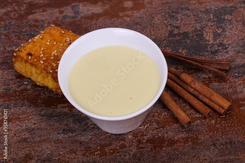 Condenced milk in the bowl with sinnamon and pastry photo