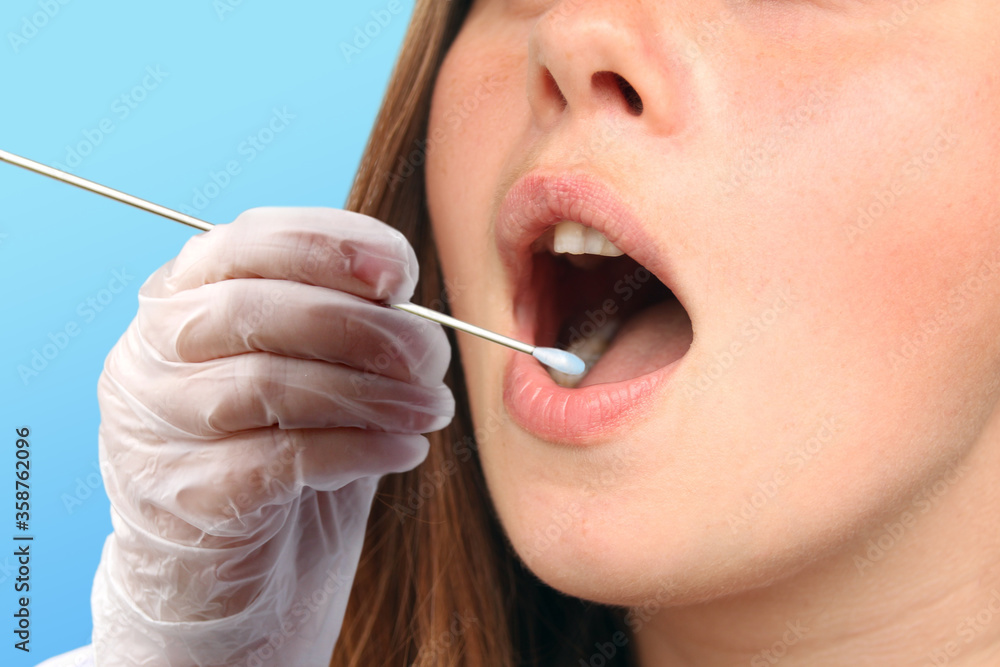 gloved technician takes a sample of a woman's saliva from her mouth for DNA analysis, concept of police investigation and medical examination, close-up gloved technician takes a sample of a woman's saliva from her mouth for DNA analysis, concept of police investigation and medical examination, close-up