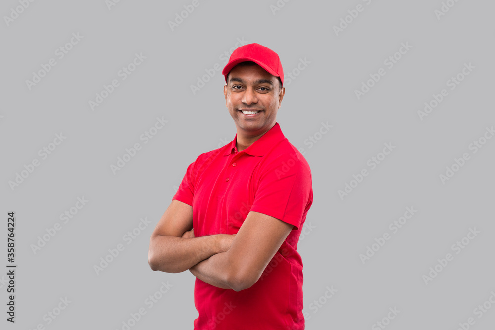 Delivery Man Standing Hands Crossed Smiling. Indian Delivery Boy in Red Uniform Isolated