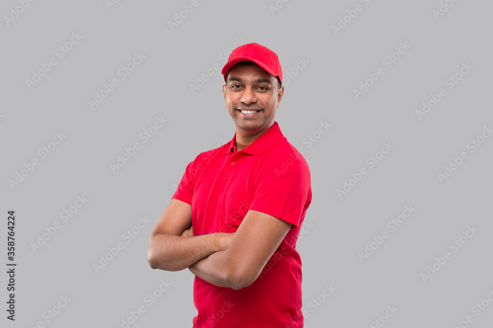 Delivery Man Standing Hands Crossed Smiling. Indian Delivery Boy in Red Uniform Isolated Delivery Man Standing Hands Crossed Smiling. Indian Delivery Boy in Red Uniform Isolated