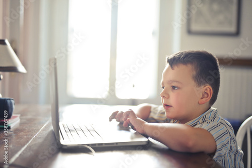 child writes on the computer at home
