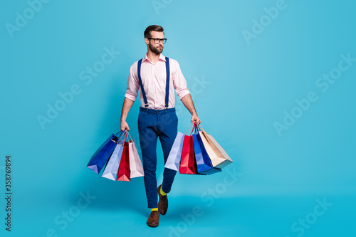 Full body photo of handsome business man worker carry many bags buy clothes vacation shopping center wear specs shirt suspenders pants boots socks isolated pastel blue color background