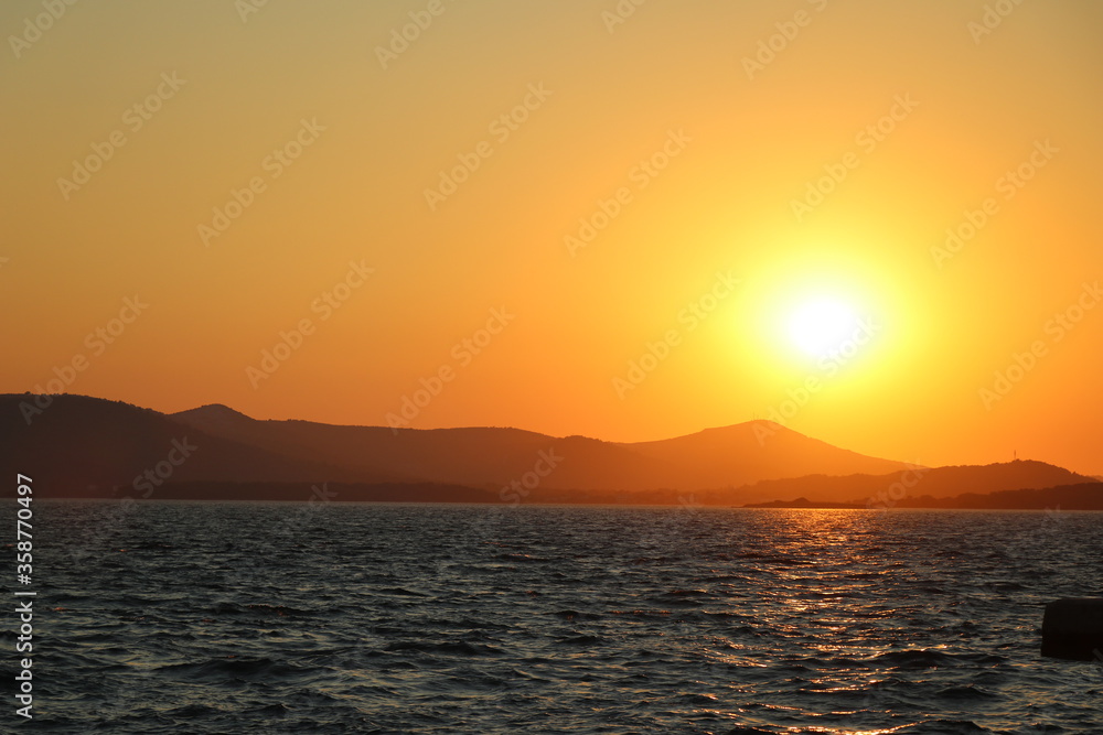 zachód słońca na tle morza i gór