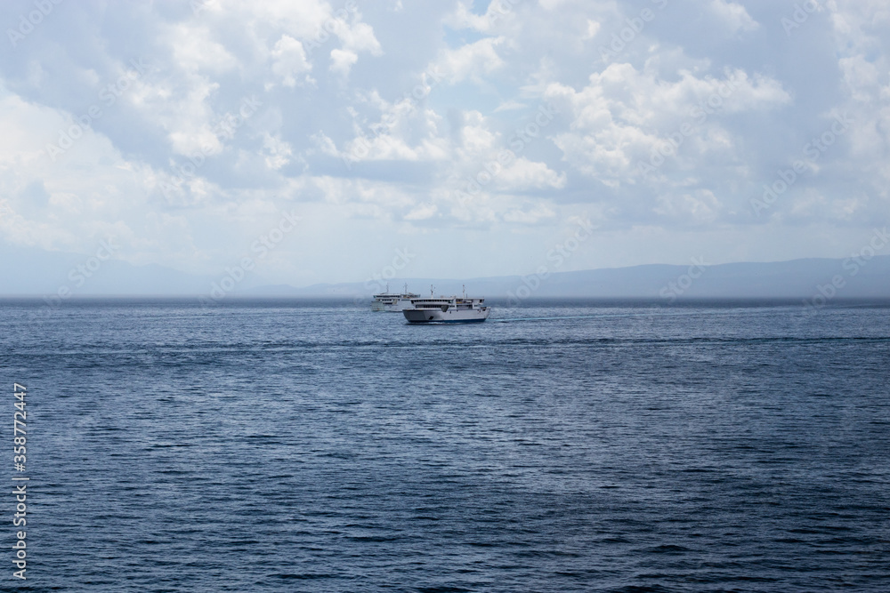 Two Croatian ferries passing each other in the open sea, sailing to the islands and to Split on a cold rainy stormy day. Dark clouds and dark seas