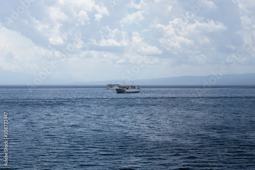 Two Croatian ferries passing each other in the open sea, sailing to the islands and to Split on a cold rainy stormy day. Dark clouds and dark seas