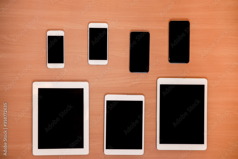 New technology on desk: different tablets and mobile phones generations, on wood desk New technology on desk: different tablets and mobile phones generations, on wood desk