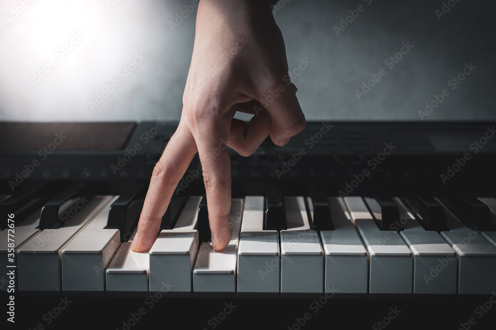 Fototapeta premium fingers press piano keys close-up, hand of a composer or musician plays a synthesizer