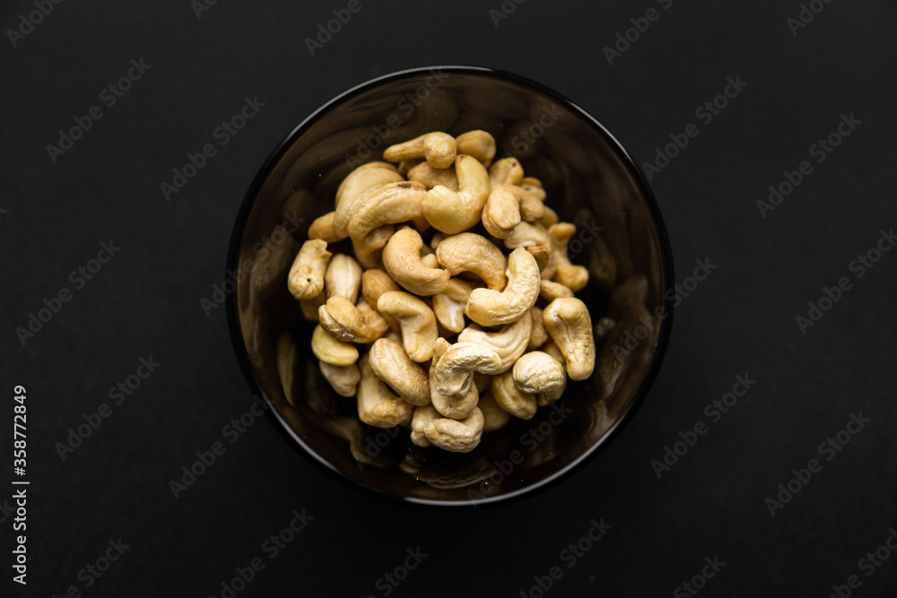 Cashew nuts in a small plate on a black table as a background. Cashew nut is a healthy vegetarian protein nutritious food. Cashew nuts in a small plate on a black table as a background. Cashew nut is a healthy vegetarian protein nutritious food.