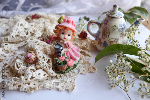 romantic composition. retro style greeting card. figurine of a cute porcelain doll, old lace and place for text