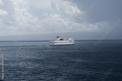 Big white Croatian ferry sailing out of Split going to the islands. Alone on the sea on a rainy storm day, dark clouds stretching into the distance © Antonio
