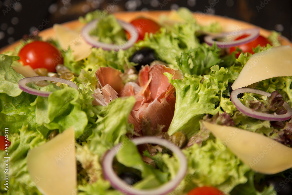 Close up of Traditional Italian pizza with jamon Serrano in focus, Parmesan cheese, black olives and cherry tomatoes on wooden background. Tasty Mediterranean rustic meal. fast food delicious dish
Close up of Traditional Italian pizza with jamon Serrano in focus, Parmesan cheese, black olives and cherry tomatoes on wooden background. Tasty Mediterranean rustic meal. fast food delicious dish