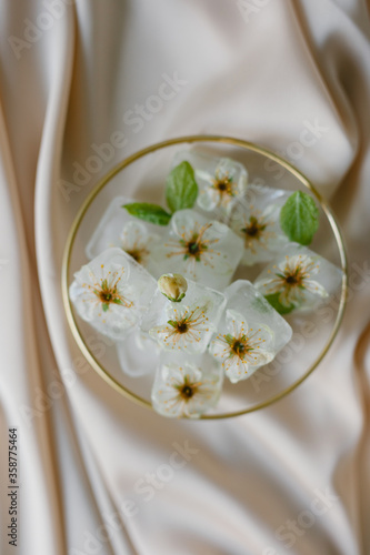 Ice cubes with flowers on silk. Fashion photography. 