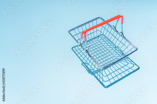 Empty metal shopping basket. Concept of consumerism, shopping symbol. Copy space trend pastel color. Hard shadows, morning light.