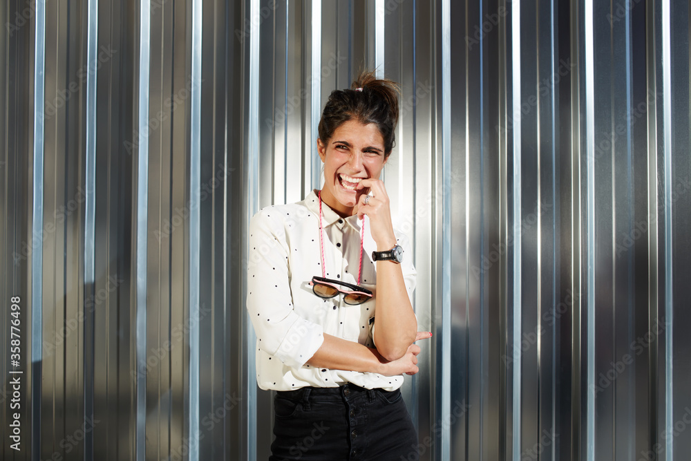 Young trendy hipster woman smiling for the camera in pose with hands crossed while standing on shiny chrome background with copy space for your text message, smiling and cheerful woman looking away Young trendy hipster woman smiling for the camera in pose with hands crossed while standing on shiny chrome background with copy space for your text message, smiling and cheerful woman looking away