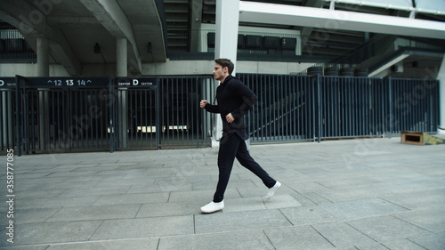 Sportsman running on urban street in slow motion. Runner male jogging outdoor