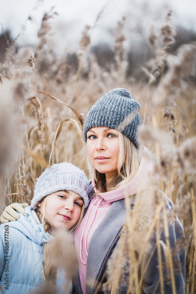 Fototapeta premium Teen girl and mom walking in the winter forest, plants, snow and cold, frosty air