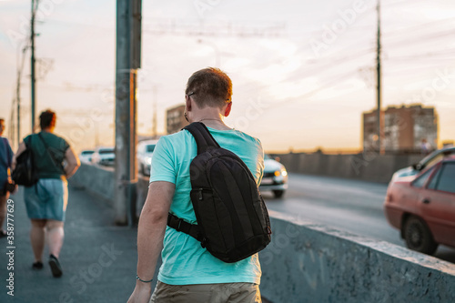 Photography A young man walks with a bag on the bridge, a common picture of pedestrians in t