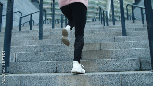 Closeup female legs running up stairs outdoor. Fitness girl climbing upstairs.