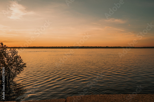 A beautiful river with a flat horizon and a boat against the red sunset sky