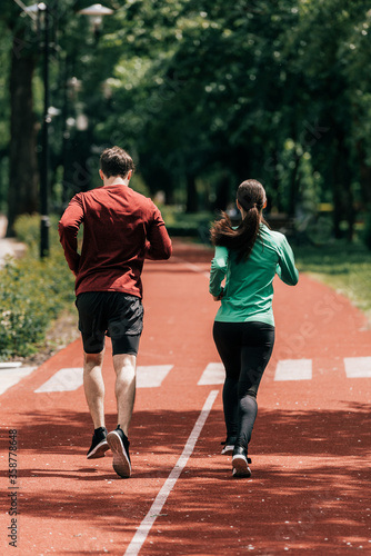 Back view of couple running on running path in park