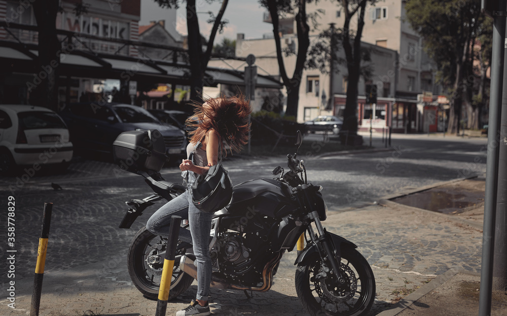 Young attractive girl with the motorbike enjoys the sun