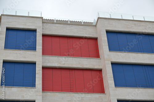 Closed, red and blue blinds of vacation apartments at the coast on the costa blanca in Spain during the corona-time.