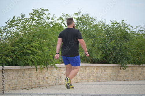 A young, overweight man is walking in his sport suit in the corona-time to lose weight. photo