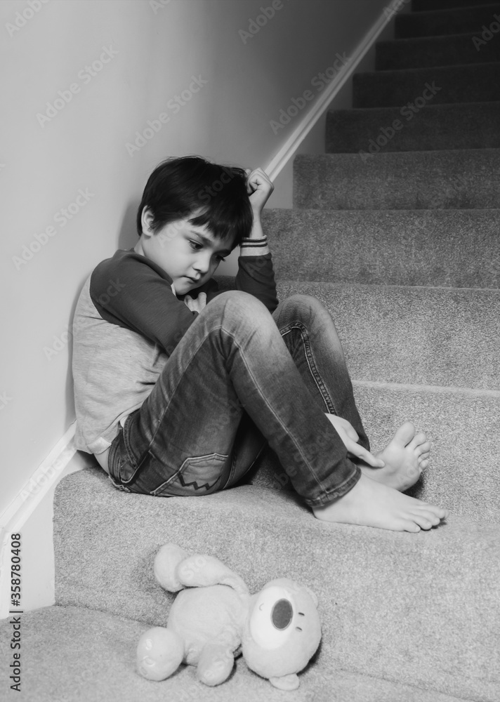 Sad boy wearing sitting on carpet staircase in the morning, Lonely kid ...