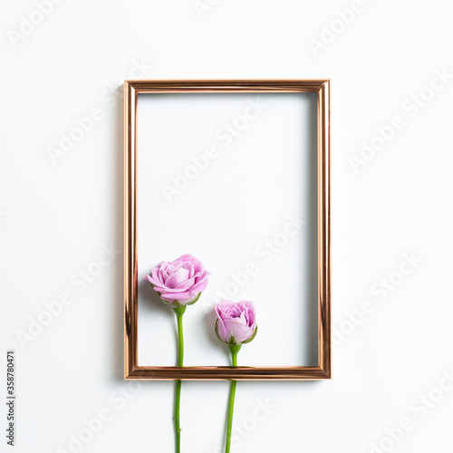 Empty photo frame with pink rose flowers on white background. Floral composition, flat lay, top view, copy space