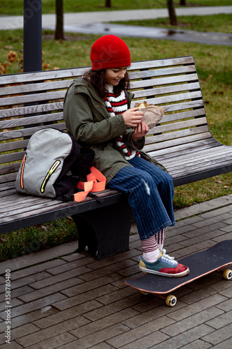 Skateboard girl take pause for juice and sandwich
