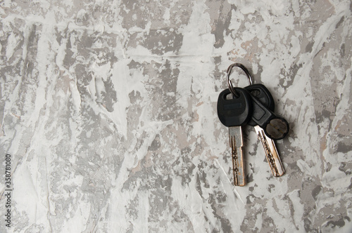 Keys to the house or apartment on a light gray concrete background with copy space, view from the top. Resale purchase concept