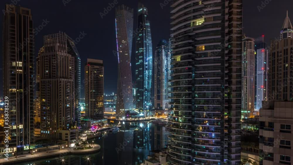 Aerial panoramic view of Dubai Marina residential and office skyscrapers with waterfront during all night timelapse with flashing lights switching off. Floating boats and yachts Aerial panoramic view of Dubai Marina residential and office skyscrapers with waterfront during all night timelapse with flashing lights switching off. Floating boats and yachts