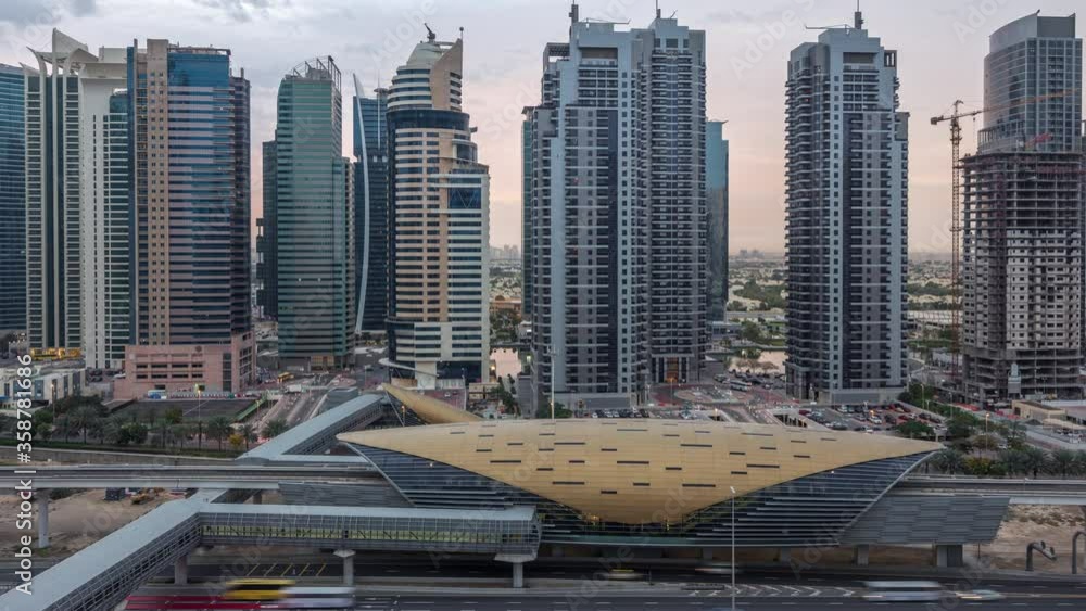 Aerial view to Sheikh Zayed road from Dubai Marina with JLT illuminated skyscrapers night to day transition timelapse, Dubai. Traffic, footbridge and metro station. United Arab Emirates Aerial view to Sheikh Zayed road from Dubai Marina with JLT illuminated skyscrapers night to day transition timelapse, Dubai. Traffic, footbridge and metro station. United Arab Emirates