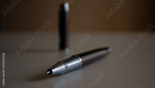 Beautiful dark pen with cap on grey office table. Concept.