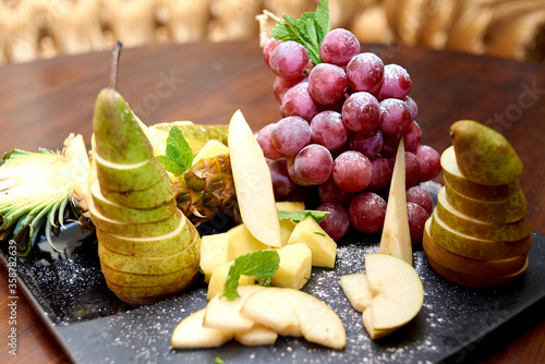 Plate with sliced fruits on servered buffet table at luxury wedding reception indoors, copy space. Catering banquet table in restaurant photo