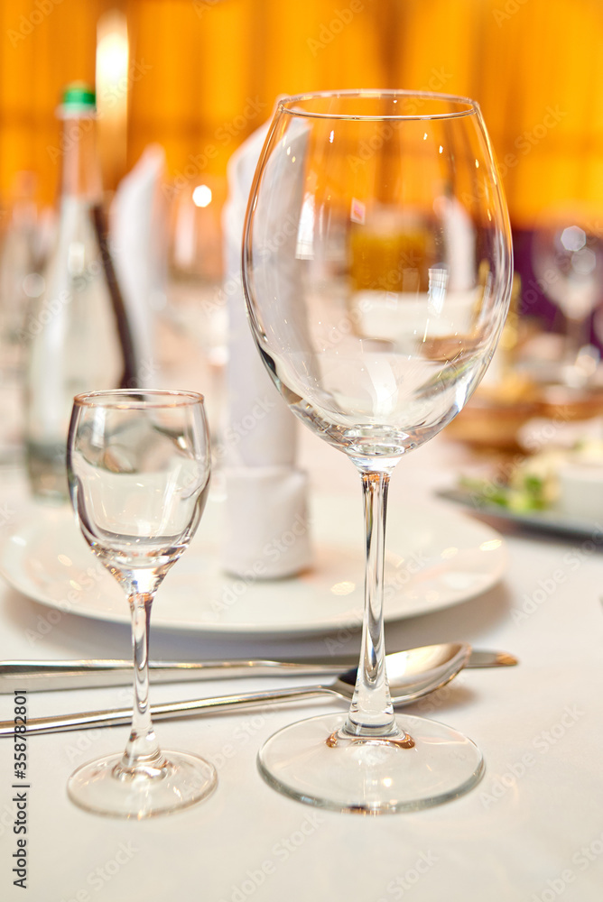 Table setting with sparkling wineglasses, plate with white napkin and cutlery on table, copy space. Place set at wedding reception. Table served for wedding banquet in restaurant Table setting with sparkling wineglasses, plate with white napkin and cutlery on table, copy space. Place set at wedding reception. Table served for wedding banquet in restaurant