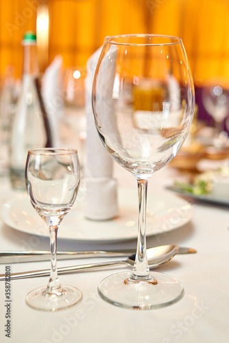 Table setting with sparkling wineglasses, plate with white napkin and cutlery on table, copy space. Place set at wedding reception. Table served for wedding banquet in restaurant