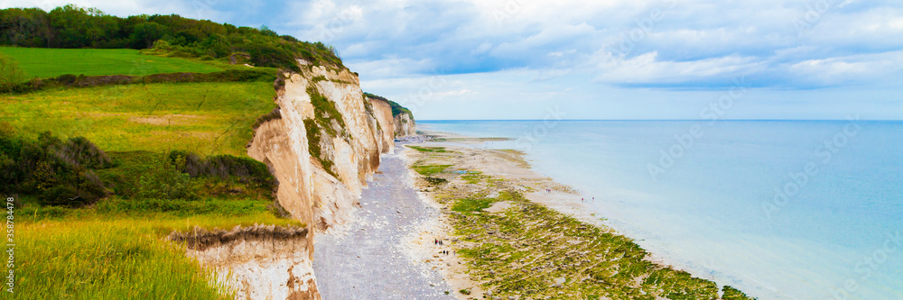 Beautiful cliffs in the north of France, Normandy region, Pourville-sur-mer town. Massive rocks, wide beach, blue water, cloudy sky. Banner