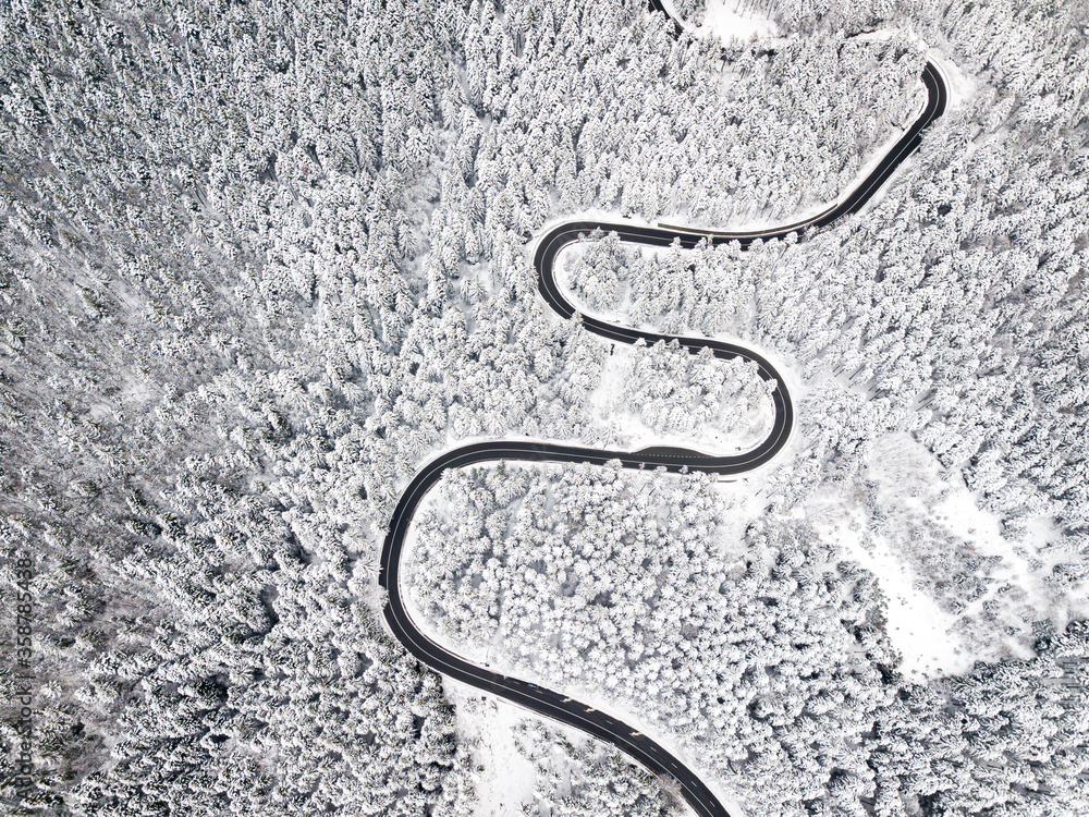 Beautiful aerial view of a curvy winding road with serpentine and white snow trees