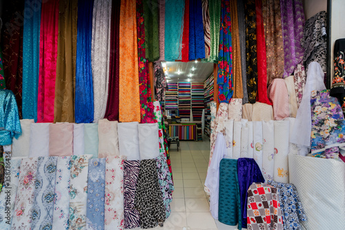 clothes for sale. clothes in shop, Rolls of fabric and textiles for sale stacked on shelves in shop, View of cloth rolls of different colors and patterns on shelves in fabric store photo