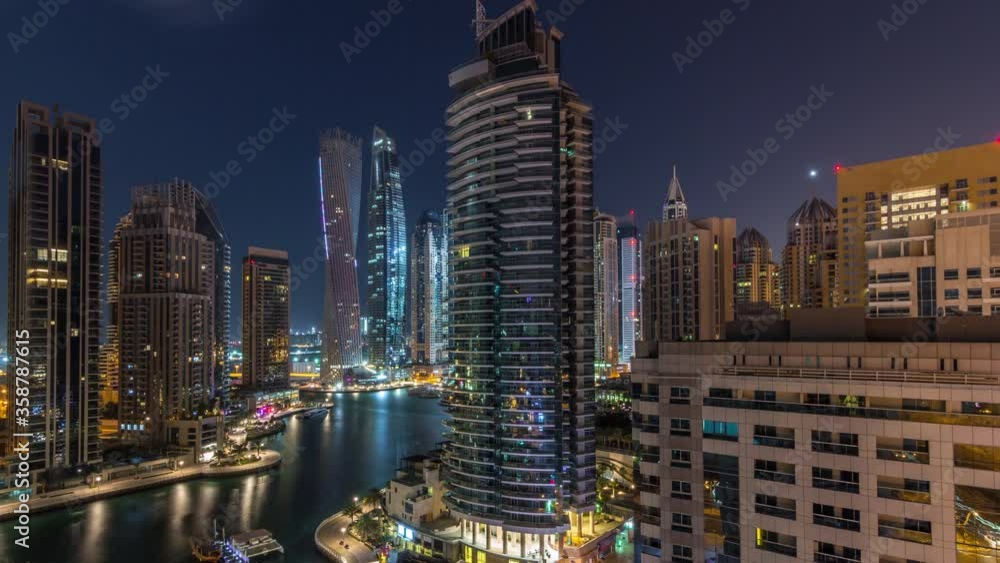 Aerial view of Dubai Marina residential and office skyscrapers with waterfront night timelapse. Floating boats and yachts Aerial view of Dubai Marina residential and office skyscrapers with waterfront night timelapse. Floating boats and yachts