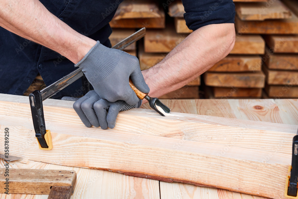 Carpenter's hands that work with cutter. Man working with plane on wooden background. Joiner work in carpentry.
