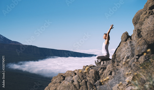 Woman doing yoga and meditating on background of natural landscape