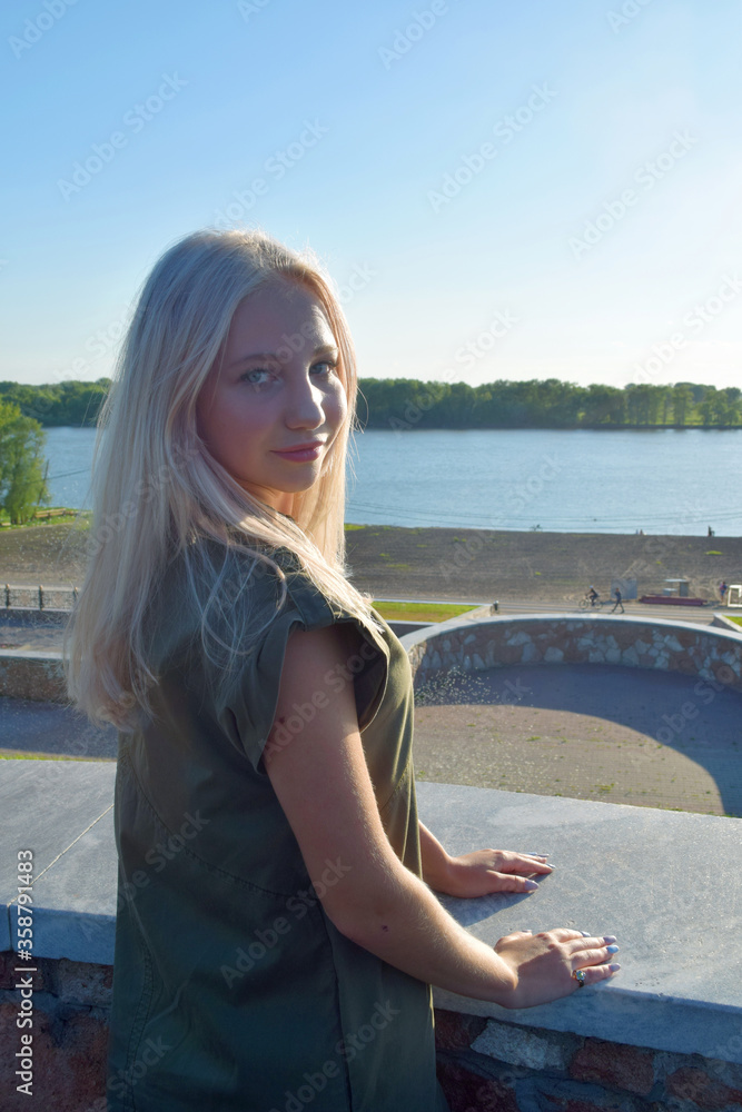 beautiful blond young woman standing in front of river