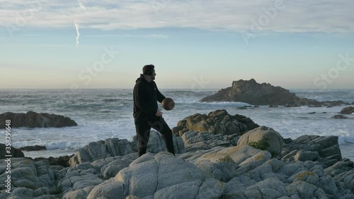 Slow motion cinematic of authentic and trendy basketball player training in black sport suit practacing with ball at sunset filled california vibes on warm summer evening