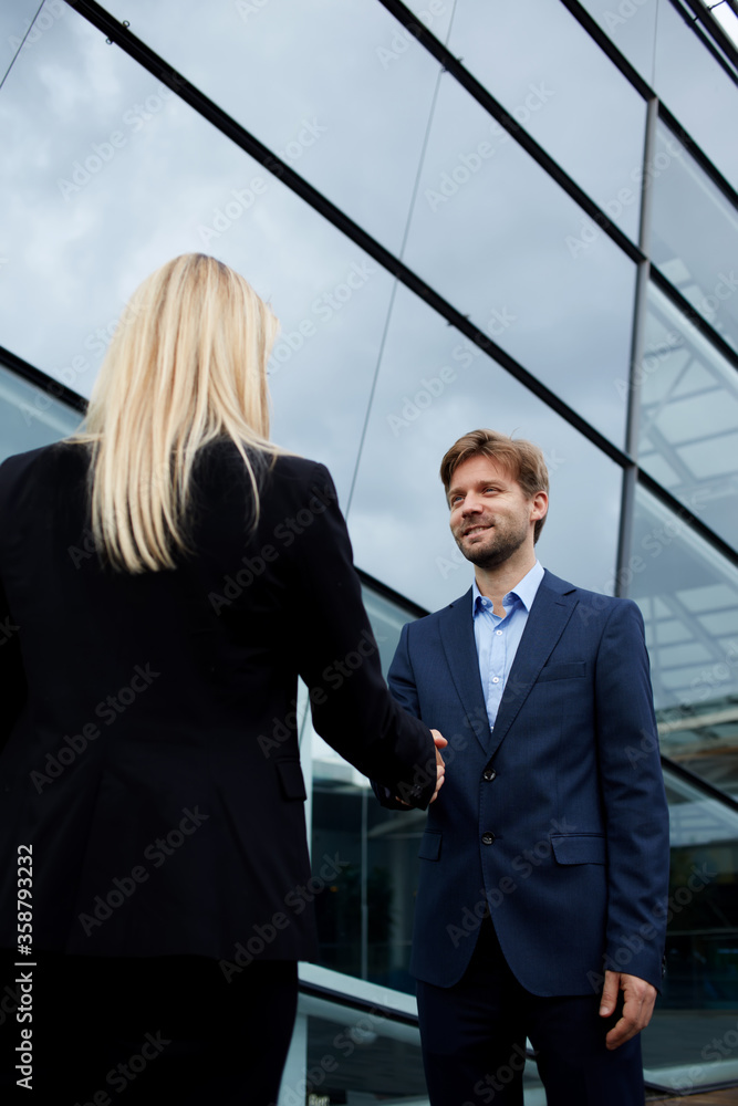 Rear view managing businesswoman shaking hand with smiling employee outside the office, business handshake and trust concept, business colleagues having agreement in conversation or discussion Rear view managing businesswoman shaking hand with smiling employee outside the office, business handshake and trust concept, business colleagues having agreement in conversation or discussion