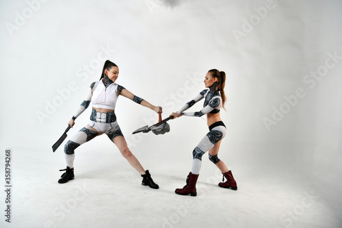 beautiful brunette girls in robotic costumes fight on battle axes and hammers